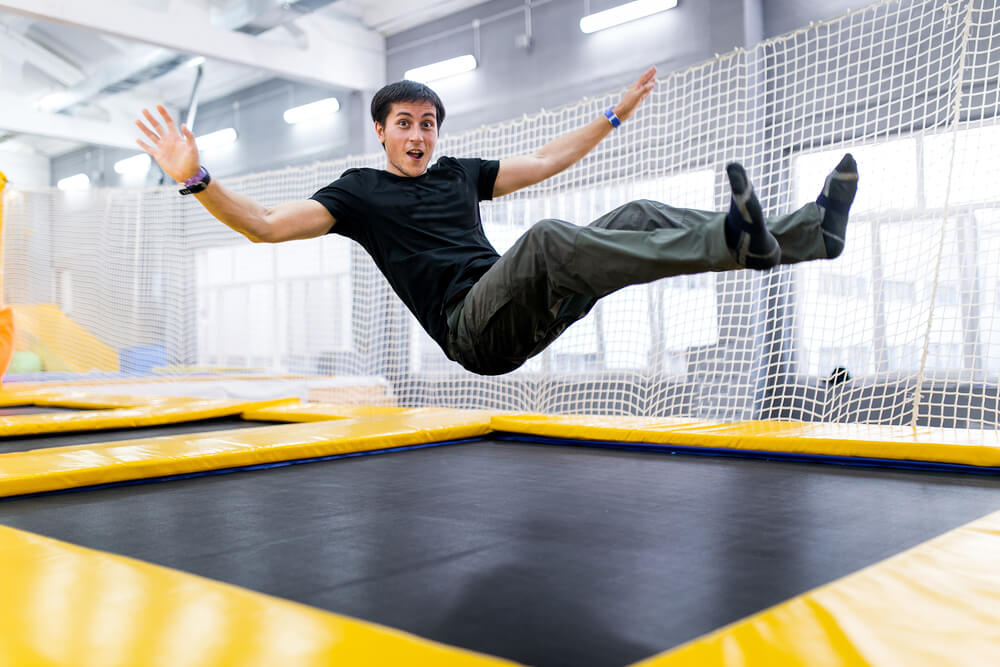 A guy jumps on a trampoline on his back