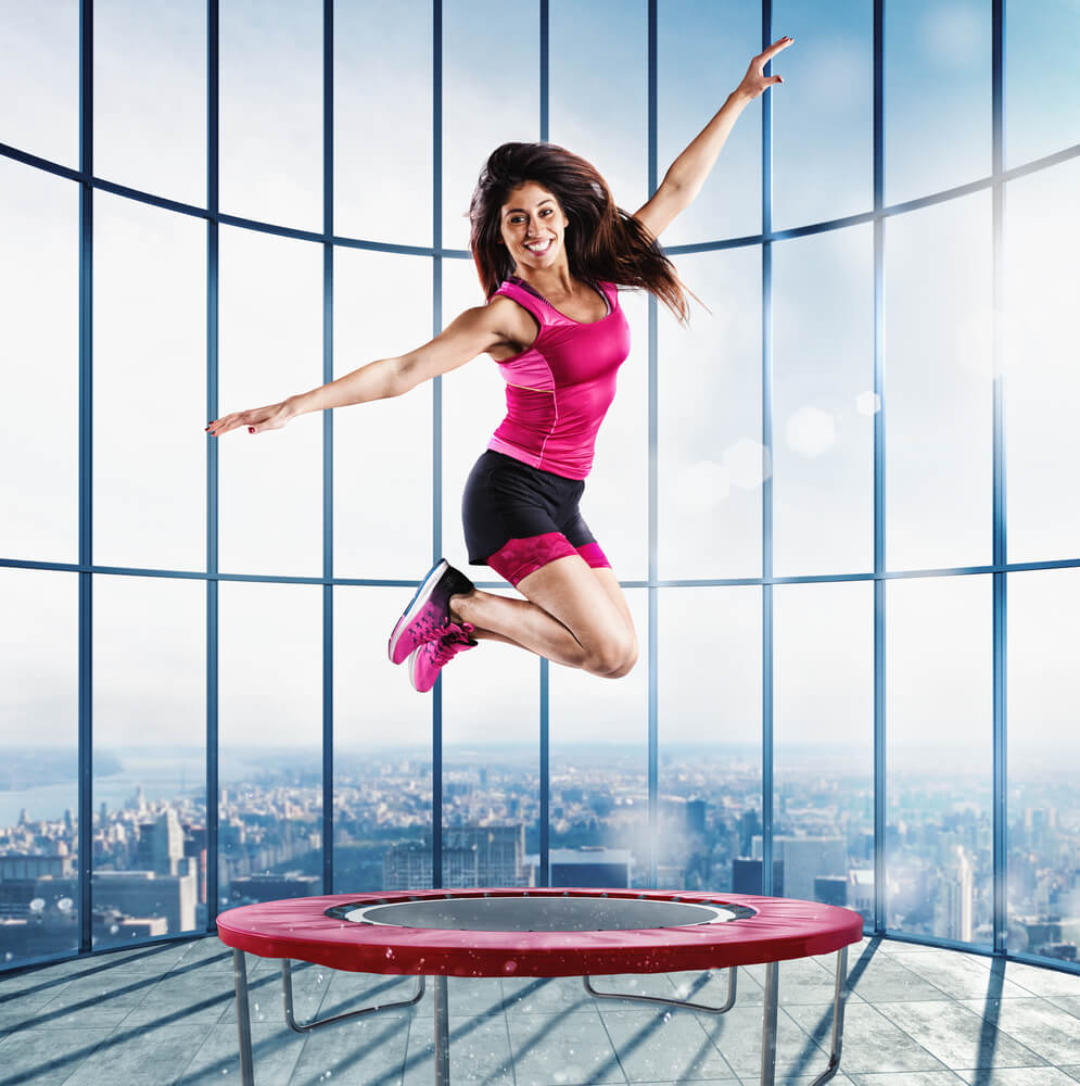 A woman jumps on a trampoline in a residential building