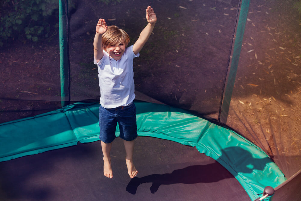 A child jumps barefoot on a trampoline