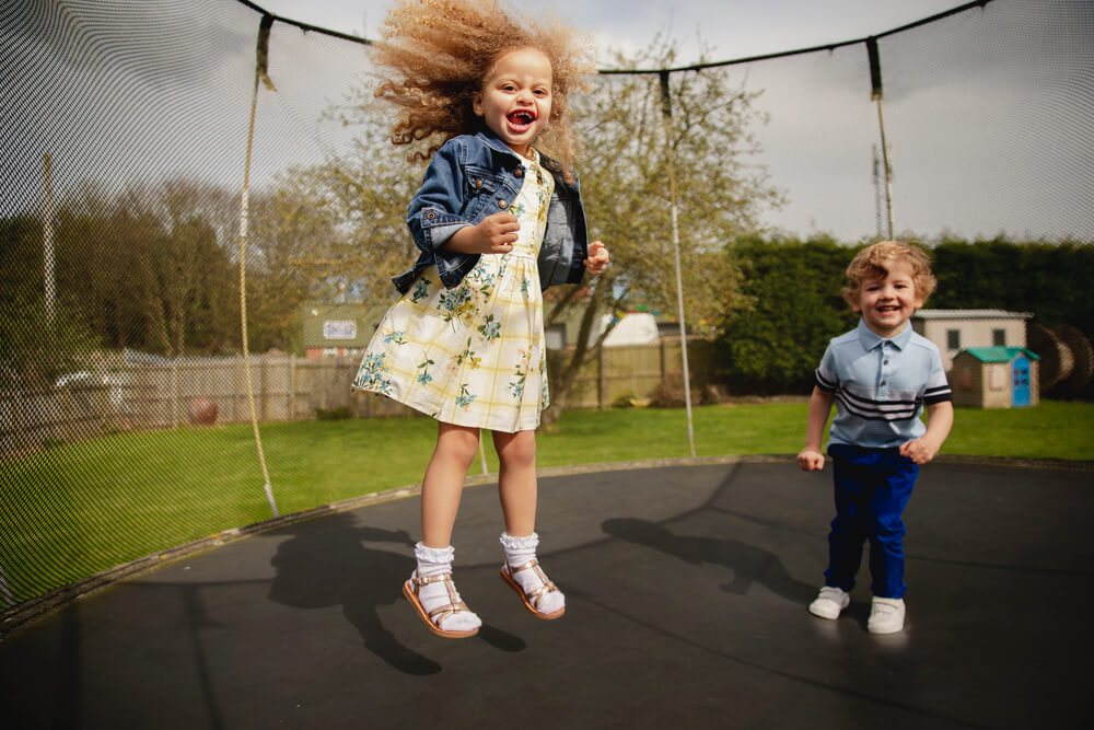 Two children jump on a trampoline