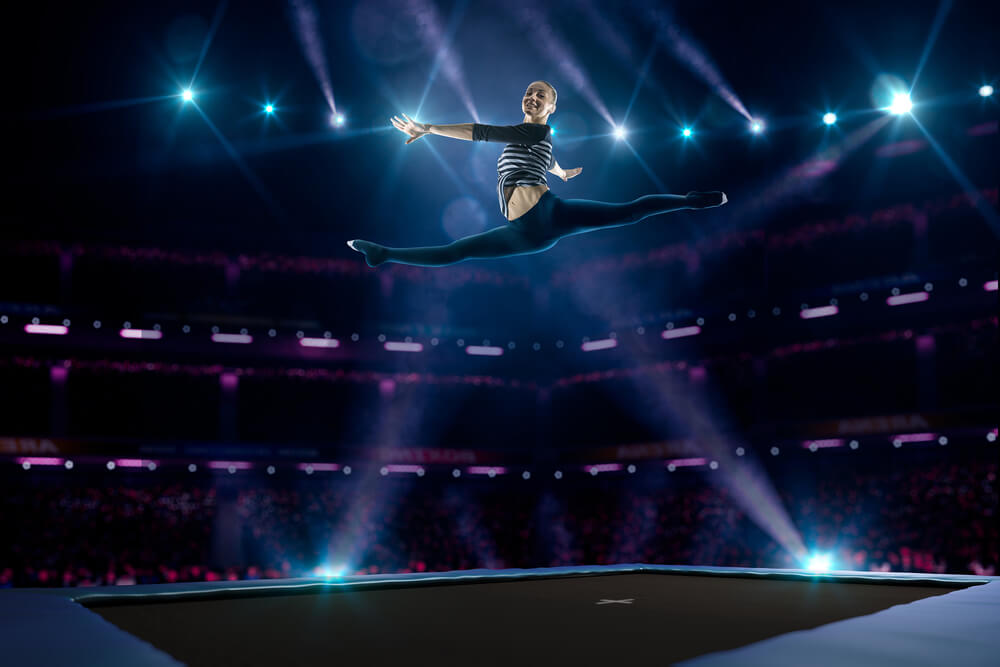 A woman jumps very high on a trampoline