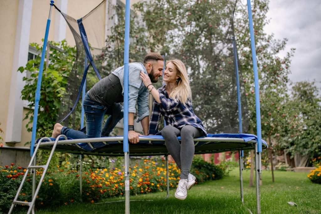 A couple sitting on a trampoline in the yard