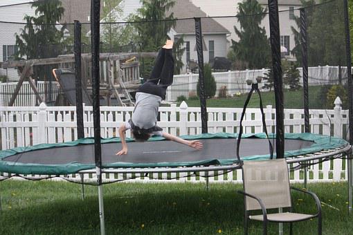 A girl jumps on a trampoline in the yard 1